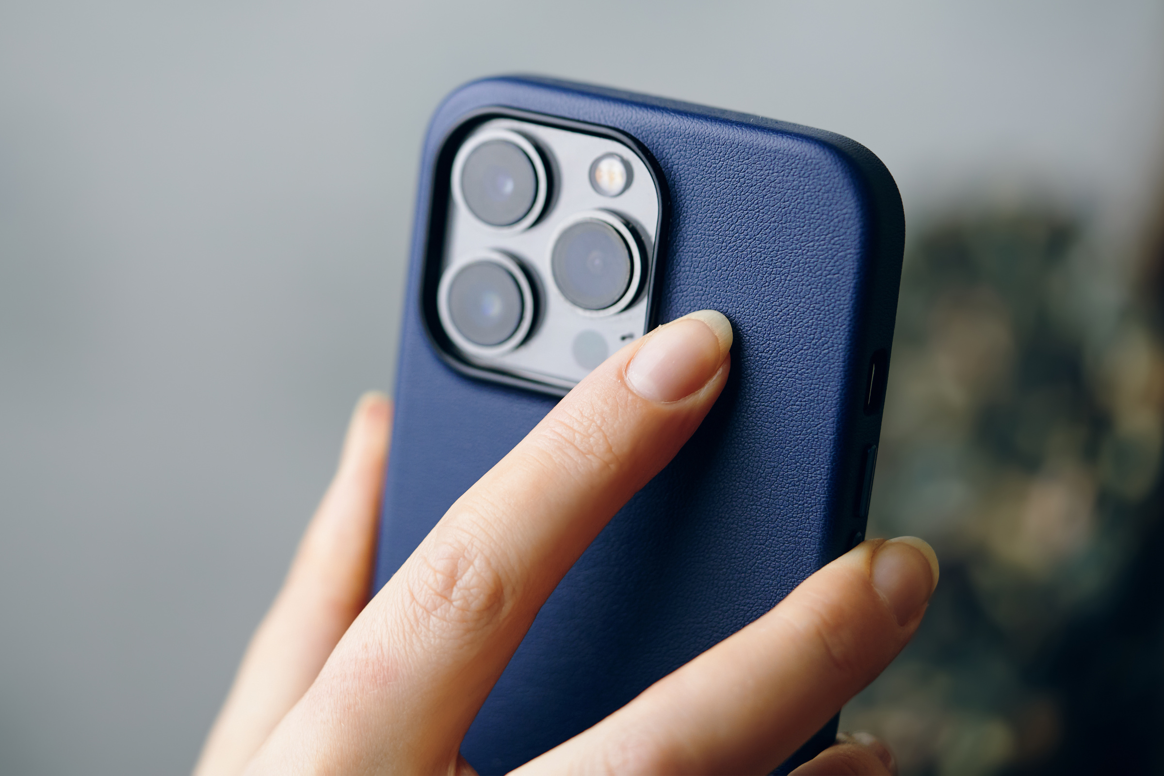 Person holds an iPhone 13 pro in a blue case.